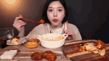 a woman is sitting at a table eating food with a wooden spoon