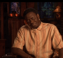 a man wearing an orange and white striped shirt is sitting in a dark room