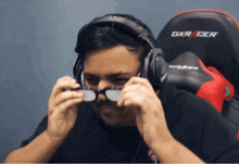 a man wearing headphones and glasses sits in a dxr cer chair