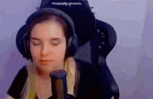 a woman is wearing headphones and sitting in a gaming chair .