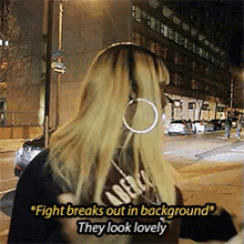 a woman wearing hoop earrings says " fight breaks out in background " and " they look lovely "