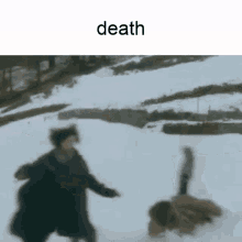 a person is laying on the ground in the snow while another person runs .