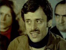 a man with a mustache is smiling and looking at something