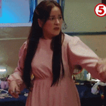 a woman in a pink dress is standing in front of a sign that says 5 on it