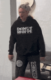 a woman wearing a hoodie that says donut shoppe on it