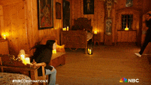 a woman is sitting in a chair in a room with candles and the nbc logo