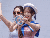 two girls are posing for a picture and one of them is wearing a sailor hat and sunglasses