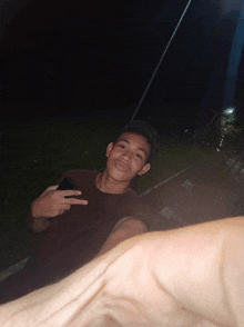 a young man giving a peace sign while holding a phone