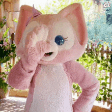 a stuffed animal in a pink and white cat costume covering one eye with its paw