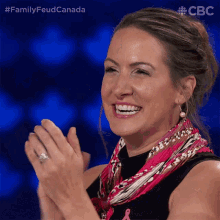 a woman applauds while wearing a pink scarf and earrings