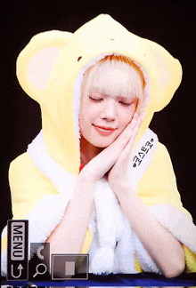 a girl wearing a yellow hooded blanket with the word menu on it