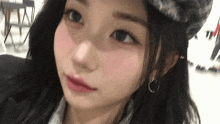 a close up of a woman wearing a hat and earrings looking at the camera .