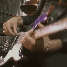 a close up of a person playing a purple guitar