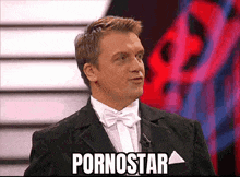 a man in a tuxedo and bow tie says pornostar on a screen