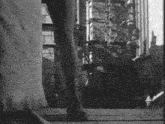 a black and white photo of a woman 's feet walking in front of a brick building .