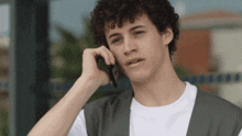 a young man with curly hair is talking on his cell phone