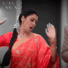 a woman in a red saree is dancing in front of a sign that says ninj
