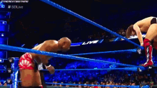 two wrestlers are fighting in a ring with a referee watching .