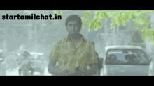 a man in a yellow shirt is standing in a busy street with the website starttamilchat.in above him