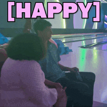 a man and a woman are sitting at a bowling alley with the words happy written above them