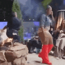 a woman is dancing on a stage wearing red boots .