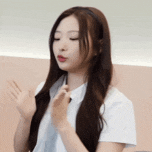 a woman with long brown hair is wearing a white shirt and a headband while waving her hands .