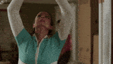 a woman in a green and white sweater is looking up at something