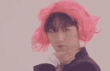 a man wearing a pink wig and a black suit is making a funny face .