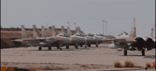 a row of fighter jets are parked on a runway and one of them has the letter a on it