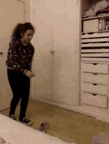 a woman in a floral sweatshirt is dancing in a room