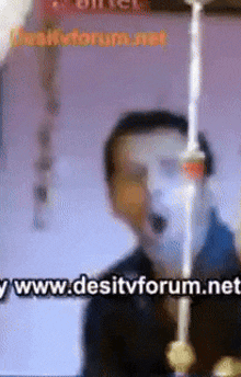 a blurred image of a man with the website www.desitvforum.net in the lower right corner