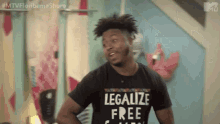 a man wearing a black shirt that says legalize free is standing in a room .