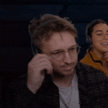 a man wearing headphones holds a pair of glasses to his mouth