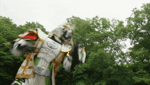 a man in a white and gold costume is standing in front of trees