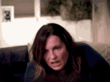 a woman is sitting on a couch making a face .