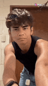 a young man wearing a black tank top and shorts is standing in front of a door ..