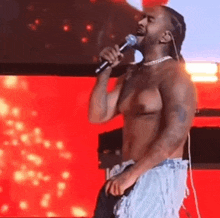 a shirtless man is singing into a microphone .