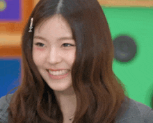 a woman with long brown hair is smiling with a green background