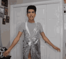 a man wearing a silver sequined vest is standing in front of a door