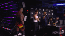a group of men are standing in front of a wall that says aew on it