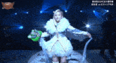 a woman in a white dress is standing in a ring holding a green glove ..