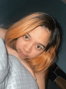 a woman with orange hair is laying on a bed looking at the camera