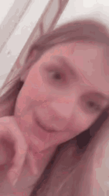 a close up of a woman taking a selfie with her hand in her mouth .