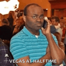 a man in a blue shirt is talking on a cell phone with the words vegas at halftime below him