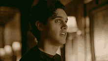 a man with curly hair is standing in a dark room looking up .