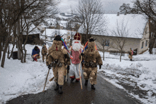 a group of people dressed in santa costumes walking down a snowy street