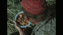 a man wearing a red hat is eating from a bowl of food