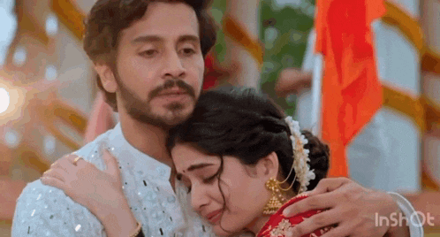 a man is hugging a woman who is crying while they are standing next to each other .