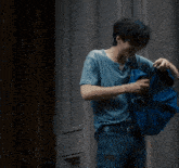 a man in a blue shirt is holding a blue backpack