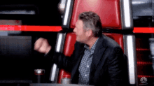 a man in a suit is sitting in a red chair .